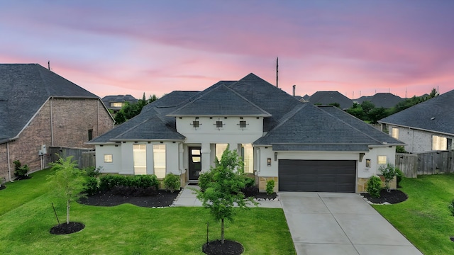 french provincial home with fence, an attached garage, stucco siding, and a front yard