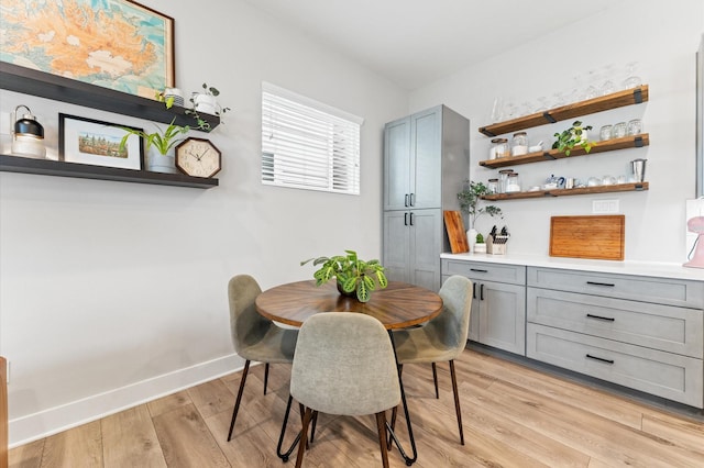 dining space with baseboards and light wood-style flooring