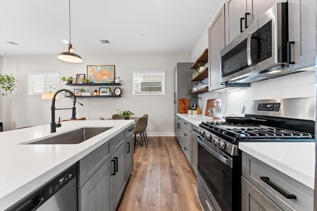 kitchen featuring stainless steel appliances, open shelves, a healthy amount of sunlight, and a sink