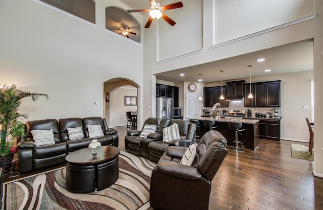 7610 River Pass Dr, Pearland, TX 77581 - living room featuring arched walkways, ceiling fan, dark wood finished floors, and a high ceiling