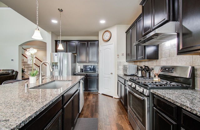 7610 River Pass Dr, Pearland, TX 77581 - kitchen with dark wood-style floors, under cabinet range hood, light stone counters, a sink, and stainless steel appliances