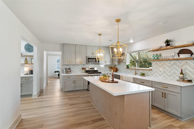 kitchen with decorative backsplash, appliances with stainless steel finishes, gray cabinets, and open shelves