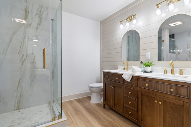 bathroom featuring double vanity, a marble finish shower, a sink, and wood finished floors
