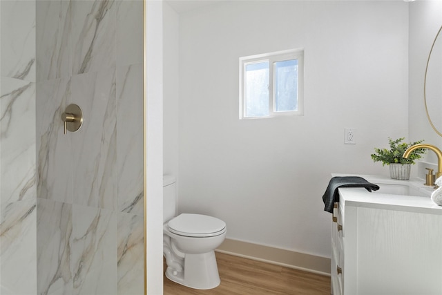bathroom with vanity, wood finished floors, toilet, baseboards, and a marble finish shower