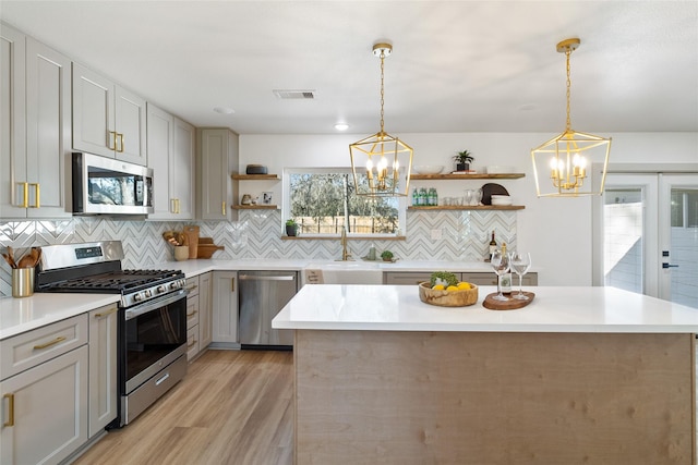 kitchen featuring open shelves, light countertops, a sink, an inviting chandelier, and stainless steel appliances