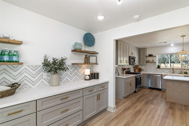 kitchen with open shelves, appliances with stainless steel finishes, light wood-style floors, backsplash, and gray cabinetry