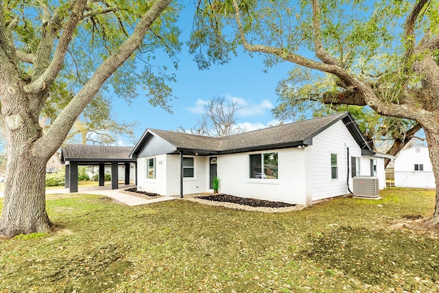 view of front of house featuring brick siding, a front lawn, roof with shingles, and central air condition unit