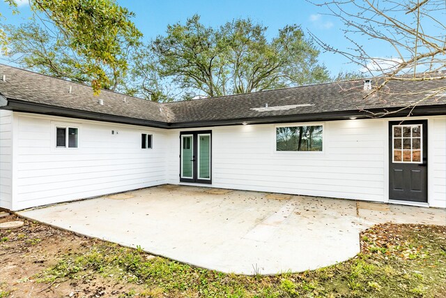 rear view of house with french doors, a patio, and roof with shingles