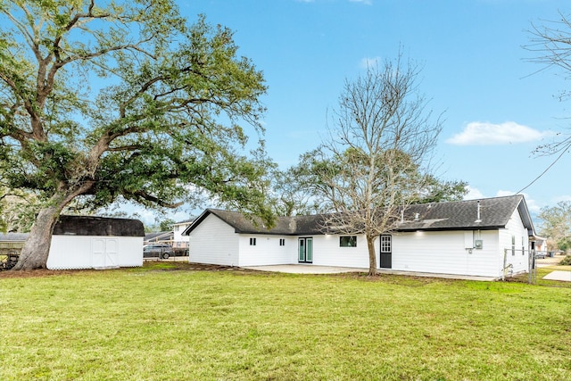 back of house featuring an outdoor structure, fence, a patio, a storage unit, and a lawn