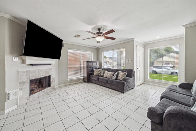 living room featuring baseboards, ornamental molding, a fireplace, and ceiling fan