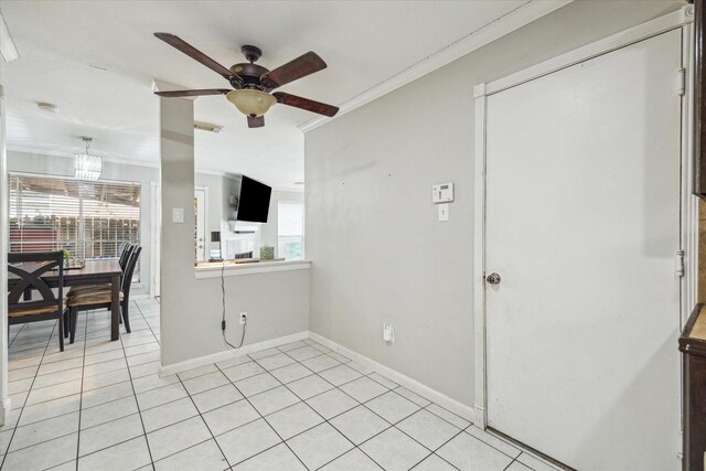interior space featuring crown molding, light tile patterned floors, ceiling fan, and baseboards