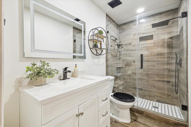 full bathroom with vanity, toilet, recessed lighting, a shower stall, and wood tiled floor