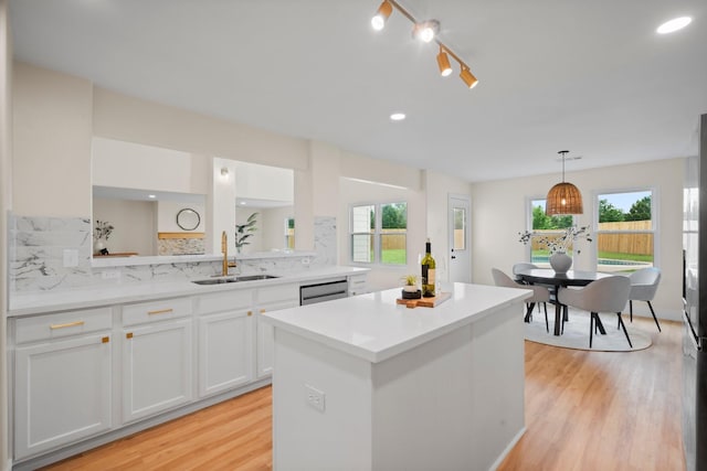 14206 Barker Bayou Ct, Cypress, TX 77429 - kitchen featuring a sink, light wood finished floors, backsplash, a center island, and white cabinets