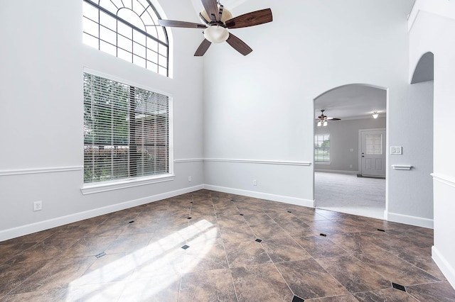 4703 Shadow Grass Dr, Katy, TX 77493 - spare room with a ceiling fan, arched walkways, a towering ceiling, and baseboards