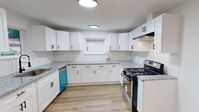 1002 Francis Dr, Pasadena, TX 77506 - kitchen with stainless steel gas stove, a sink, dishwashing machine, under cabinet range hood, and white cabinetry