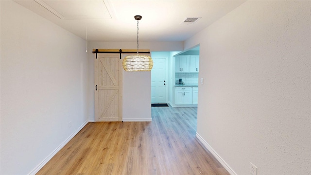 1002 Francis Dr, Pasadena, TX 77506 - unfurnished dining area featuring light wood-style floors, a barn door, and baseboards