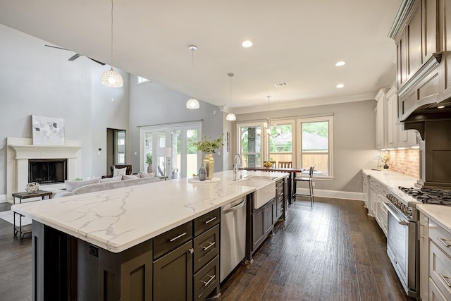 kitchen with baseboards, dark wood-style floors, light stone counters, a sink, and appliances with stainless steel finishes