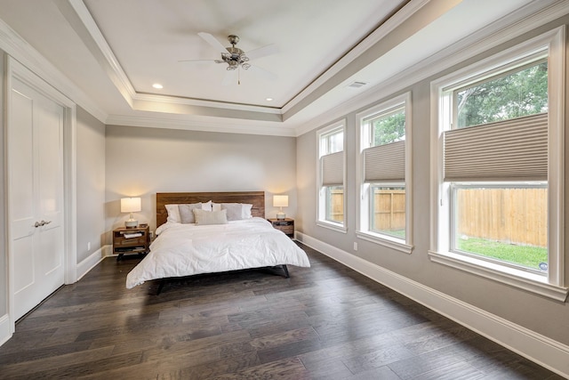 bedroom featuring a tray ceiling, dark wood-style floors, and baseboards