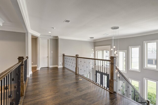 corridor featuring baseboards, an upstairs landing, wood finished floors, visible vents, and ornamental molding
