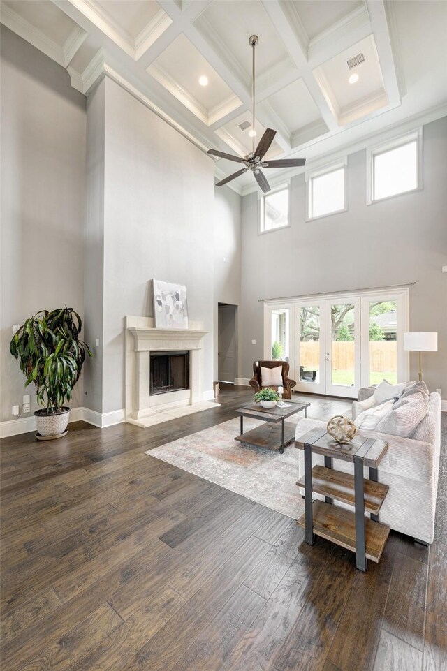 living room with coffered ceiling, a ceiling fan, dark wood finished floors, and a towering ceiling