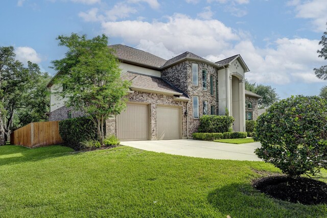 view of front of house featuring a front lawn, fence, brick siding, an attached garage, and driveway