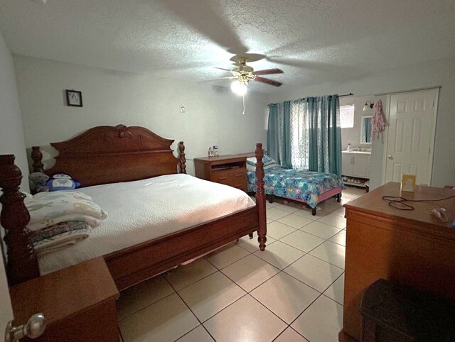 bedroom with light tile patterned floors, a ceiling fan, a textured ceiling, and connected bathroom