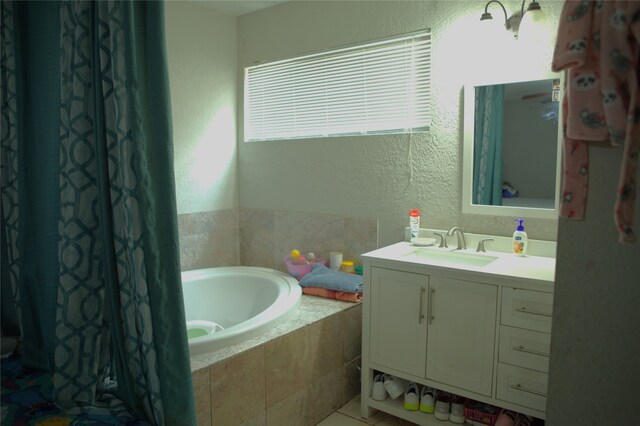 full bathroom with a textured wall, a bath, and vanity
