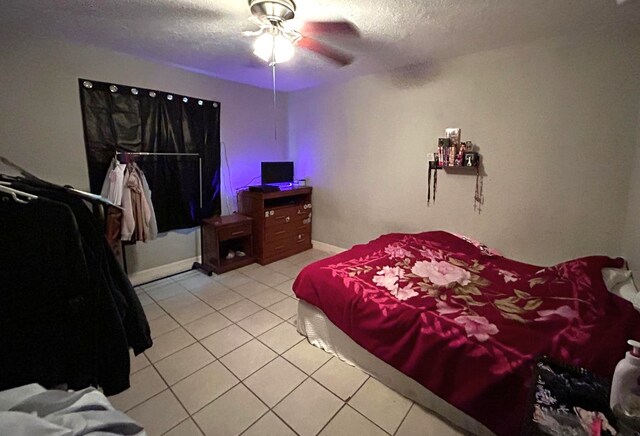 bedroom with a textured ceiling, ceiling fan, and light tile patterned floors