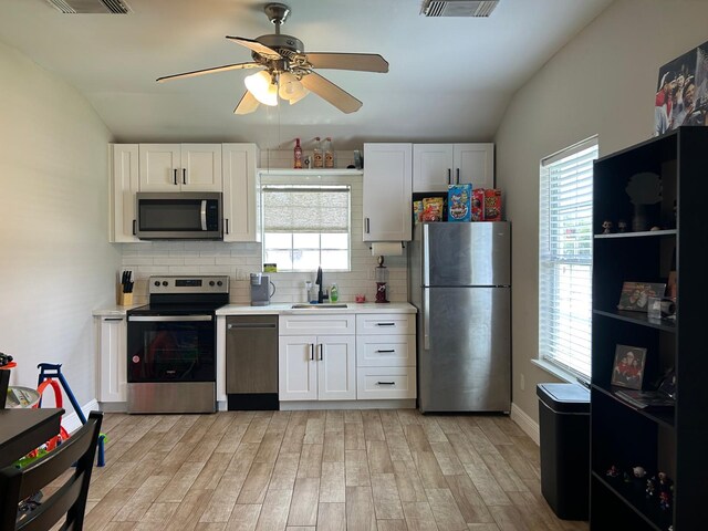 kitchen featuring decorative backsplash, a sink, light countertops, lofted ceiling, and stainless steel appliances