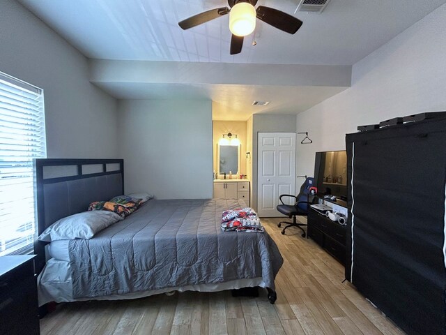 bedroom with light wood-style floors, ensuite bathroom, visible vents, and ceiling fan