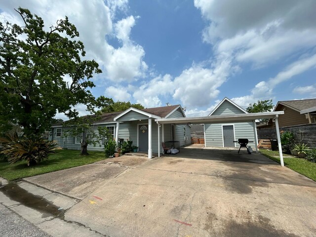 view of front of property featuring a carport, covered porch, a front yard, and concrete driveway