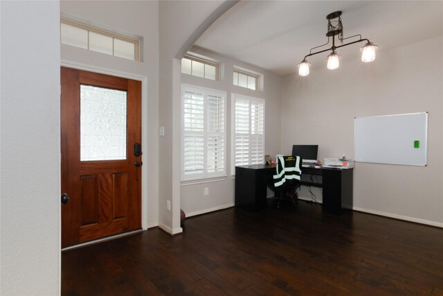 entrance foyer with arched walkways, baseboards, a wealth of natural light, and hardwood / wood-style flooring