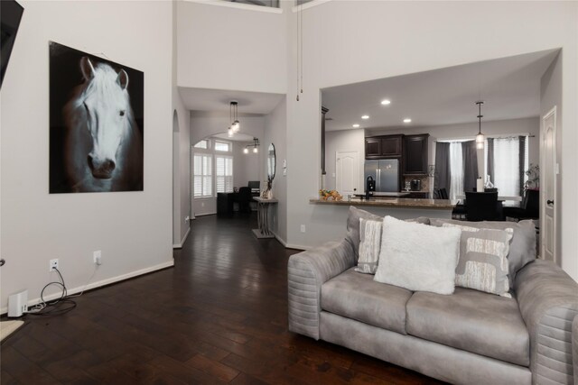 living room with baseboards, recessed lighting, dark wood finished floors, and a towering ceiling