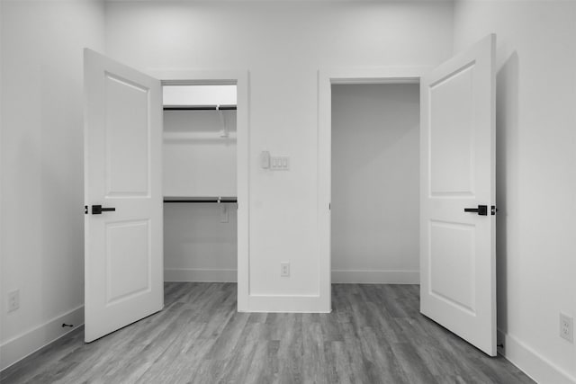unfurnished bedroom with baseboards, wood finished floors, and a closet