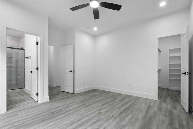 unfurnished bedroom with recessed lighting, baseboards, a walk in closet, and wood finished floors