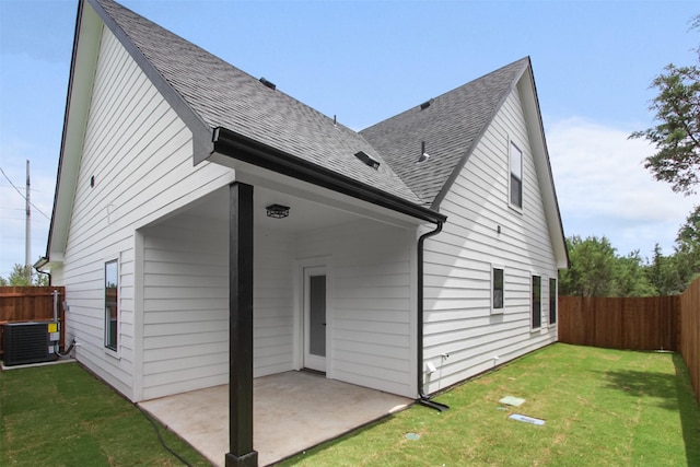 rear view of property featuring a yard, a shingled roof, a fenced backyard, and a patio area
