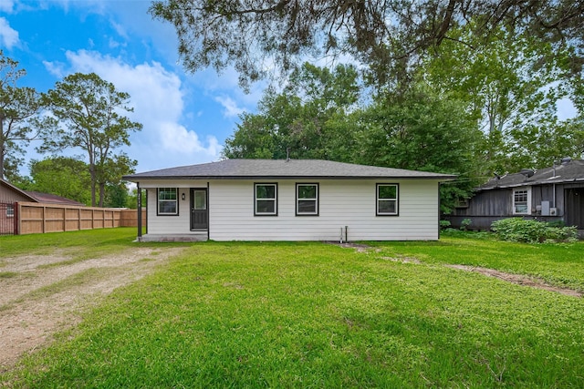 rear view of house with fence and a lawn