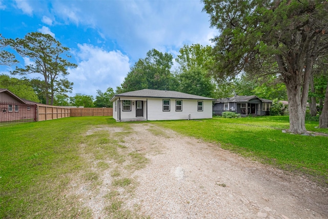 exterior space featuring a lawn, fence, and dirt driveway