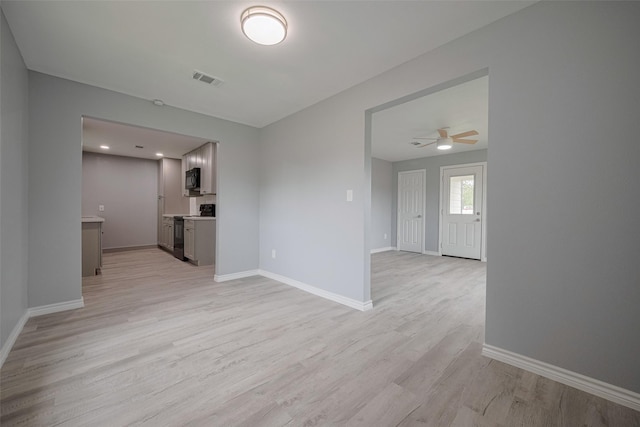 interior space featuring light wood-type flooring, a ceiling fan, baseboards, and visible vents