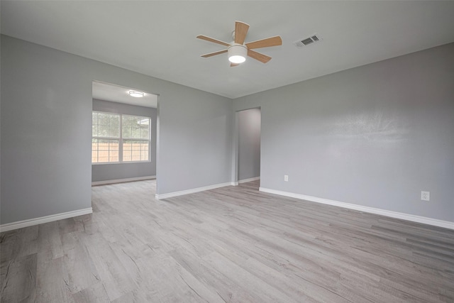 spare room featuring visible vents, a ceiling fan, baseboards, and wood finished floors