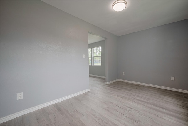 spare room with baseboards and wood finished floors
