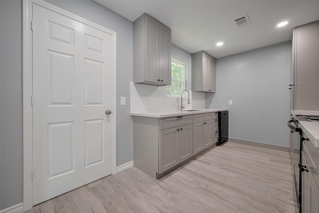 kitchen with visible vents, a sink, light wood finished floors, and gray cabinetry