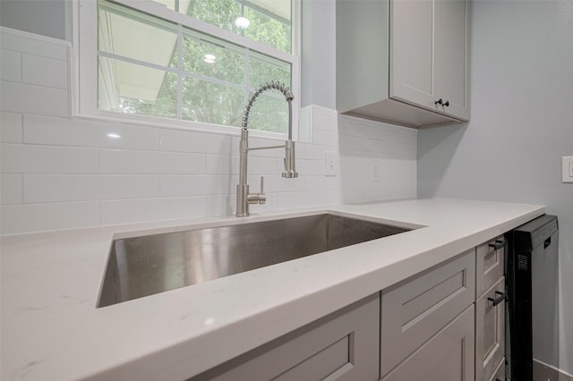 kitchen featuring a sink, light stone counters, and tasteful backsplash