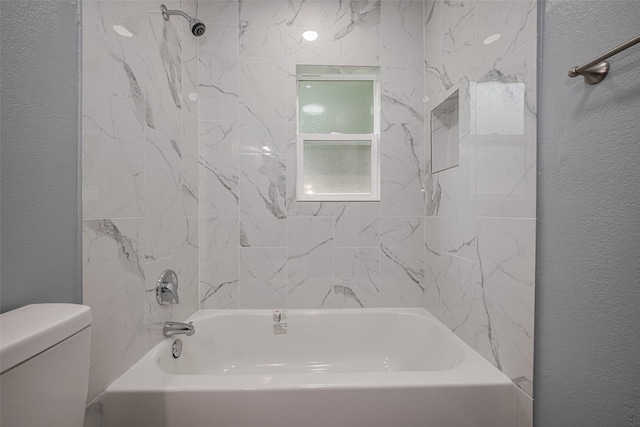 bathroom with a textured wall, toilet, and shower / washtub combination