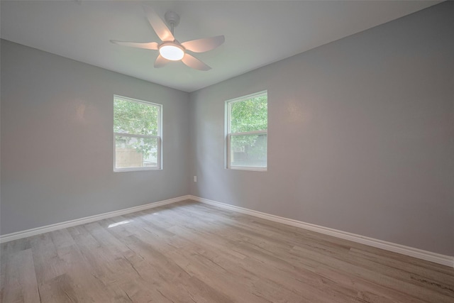 empty room with baseboards, ceiling fan, and light wood-type flooring