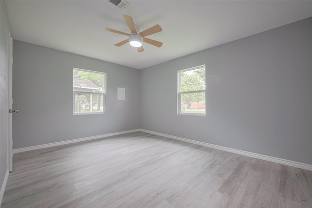 unfurnished room featuring baseboards, visible vents, a healthy amount of sunlight, and wood finished floors