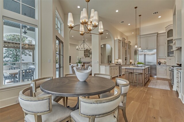 dining area with visible vents, arched walkways, a chandelier, light wood-style floors, and recessed lighting