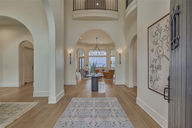entrance foyer with arched walkways, baseboards, and wood finished floors