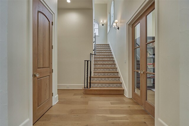 stairs with french doors, recessed lighting, baseboards, and wood finished floors