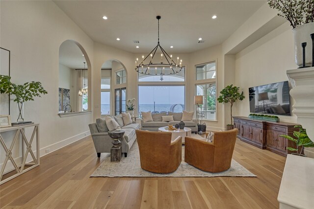 living area featuring arched walkways, light wood finished floors, and a wealth of natural light